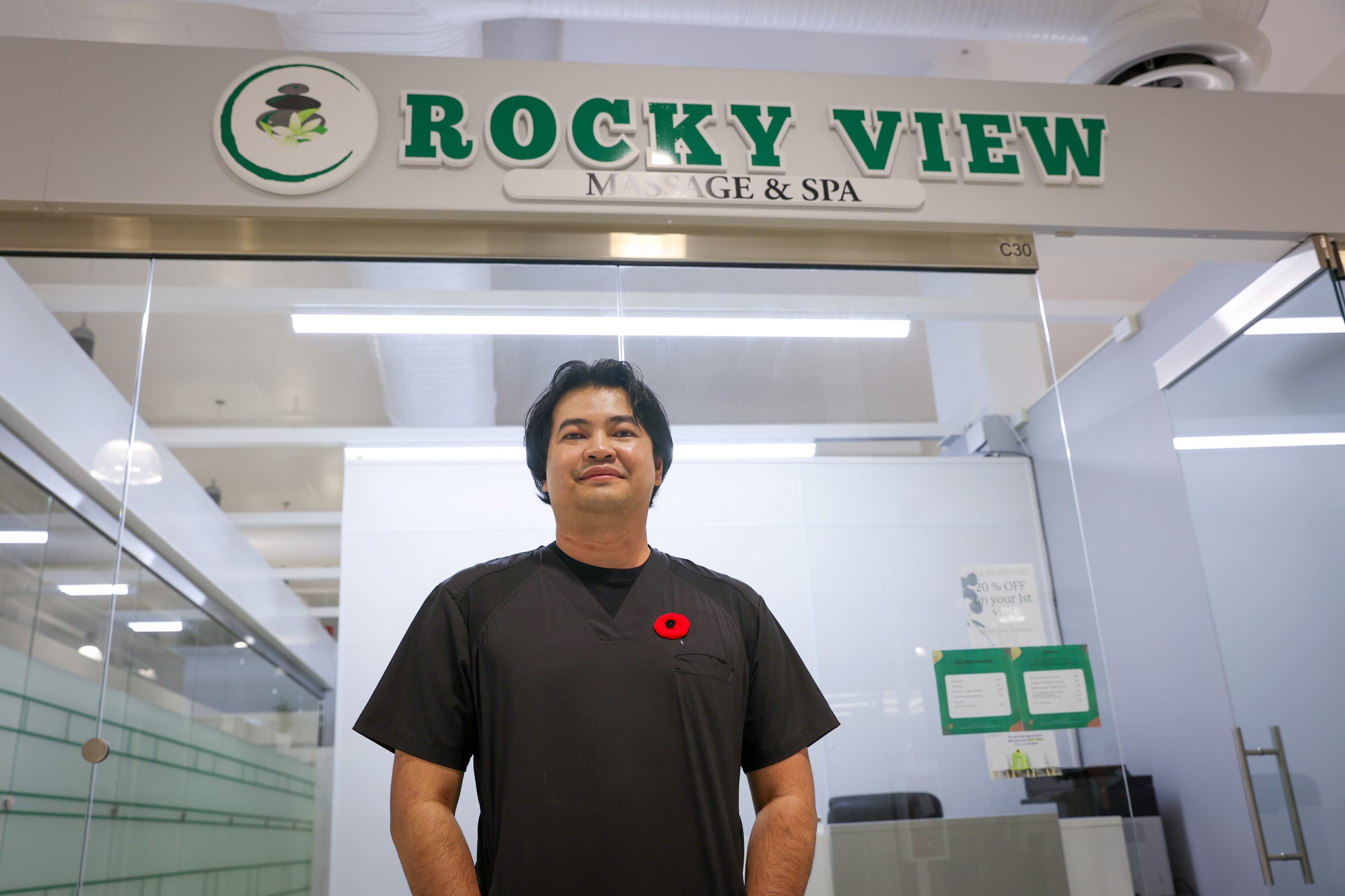 Emmanuel, a young Filipino man stands outside of the spa he co-owns, Rockyview Massage and Spa, in New Horizon Mall outside of Calgary ,Alberta, Canada