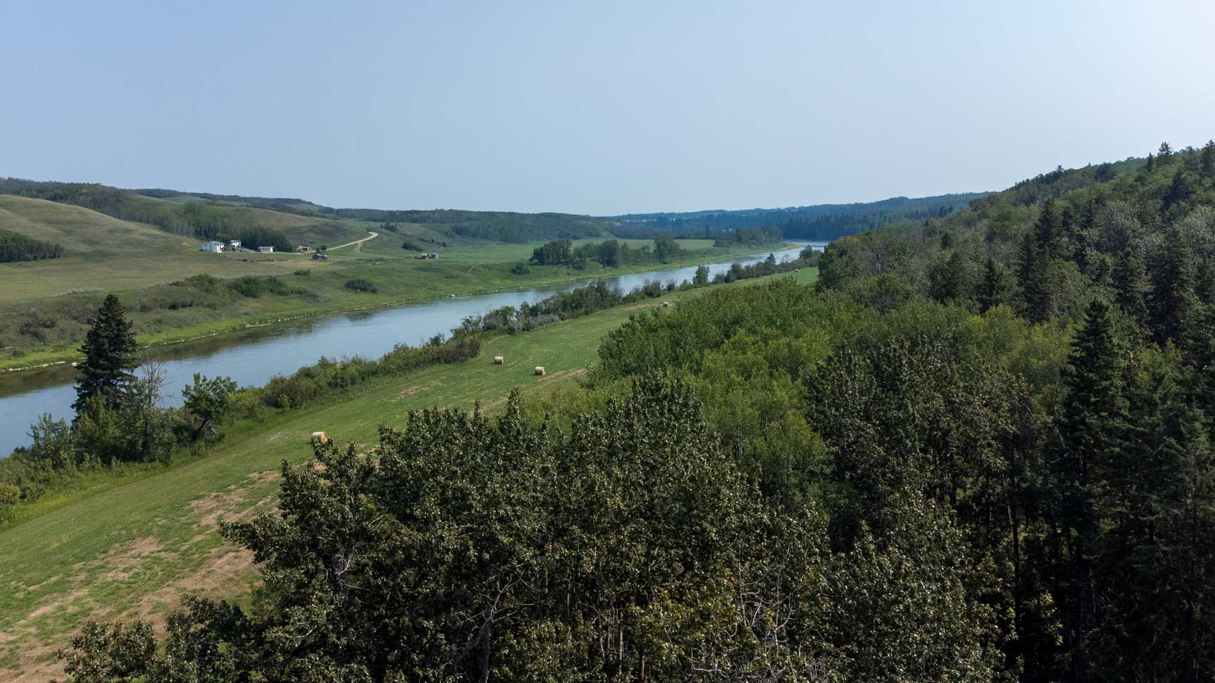 A blue sky is pictured behind rolling hills and the Red Deer River in Red Deer County, in Alberta, Canada