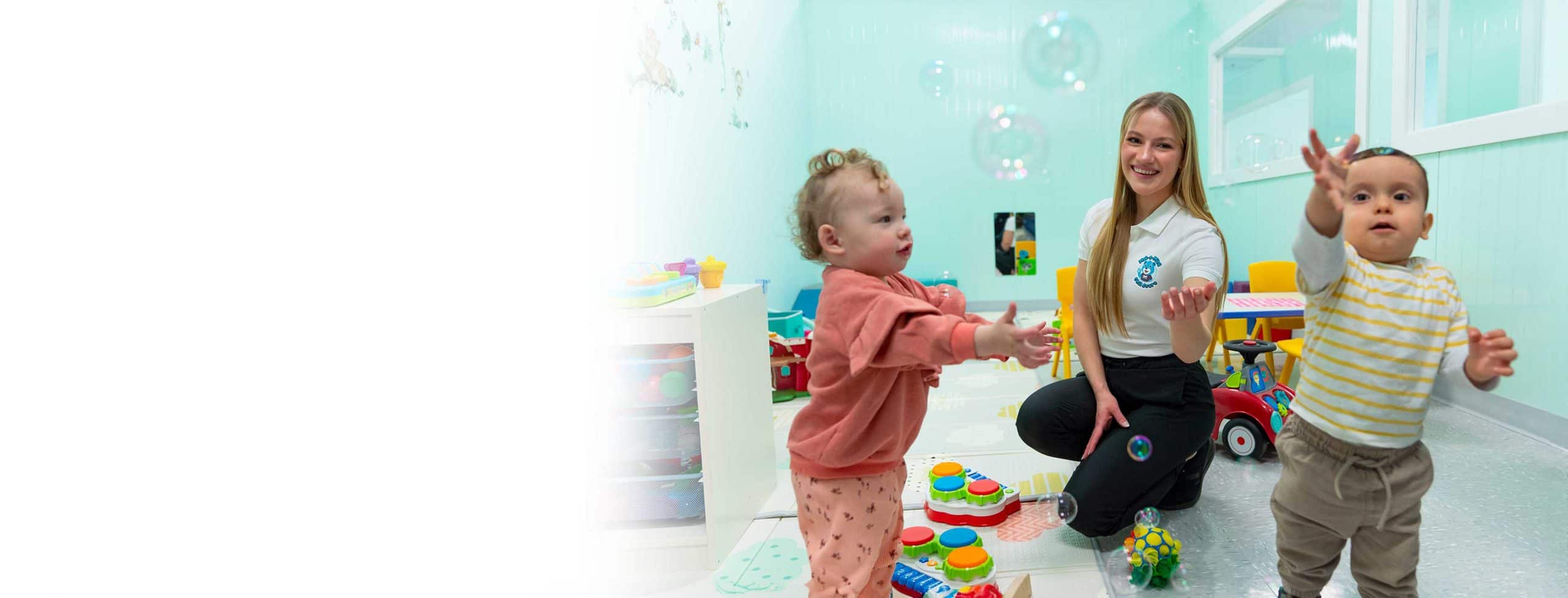 A woman training at MaKami for her early childhood education (ECE) diploma with two young children playing in a daycare