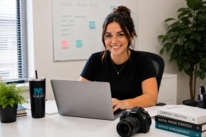 MaKami College student planning social media content on a laptop beside a camera and digital marketing books