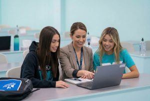 MaKami College instructor supporting two students using a laptop in a classroom