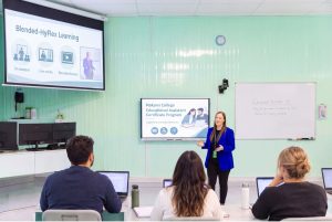 Instructor teaching Educational Assistant Certificate Program students in MaKami College’s Calgary HyFlex classroom, with in-person, live online and recorded lesson options shown on screen.