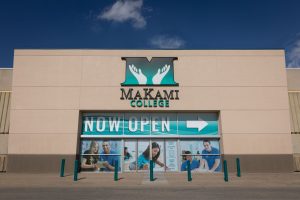 Exterior of a MaKami College campus displaying the college logo and a “Now Open” sign.
